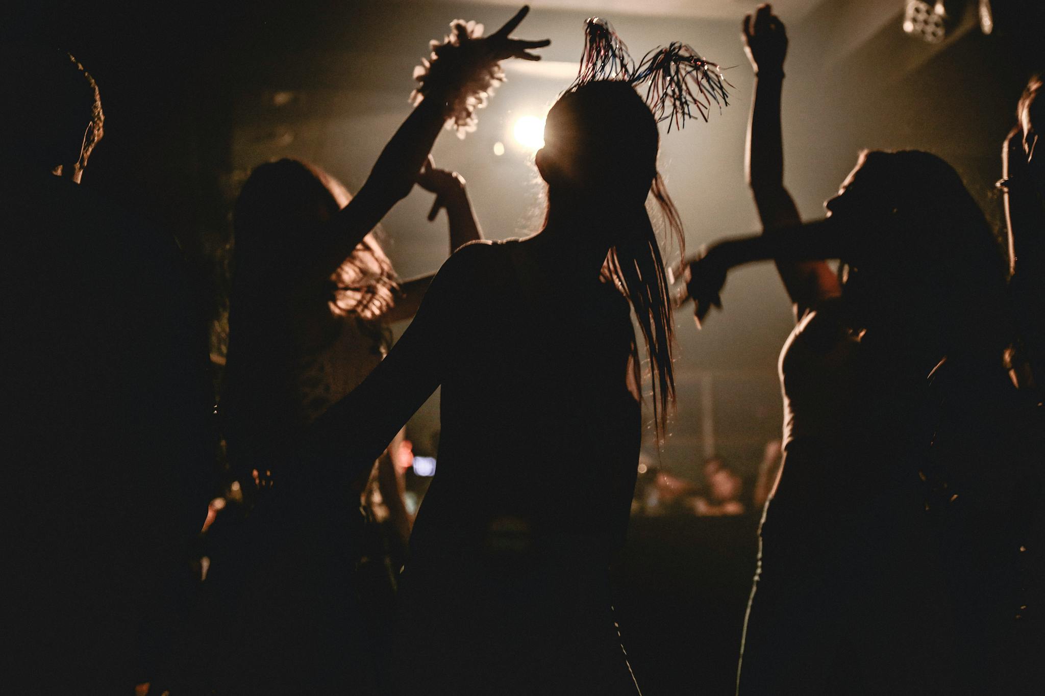Silhouetted partygoers dancing with dynamic lighting at a lively club night.